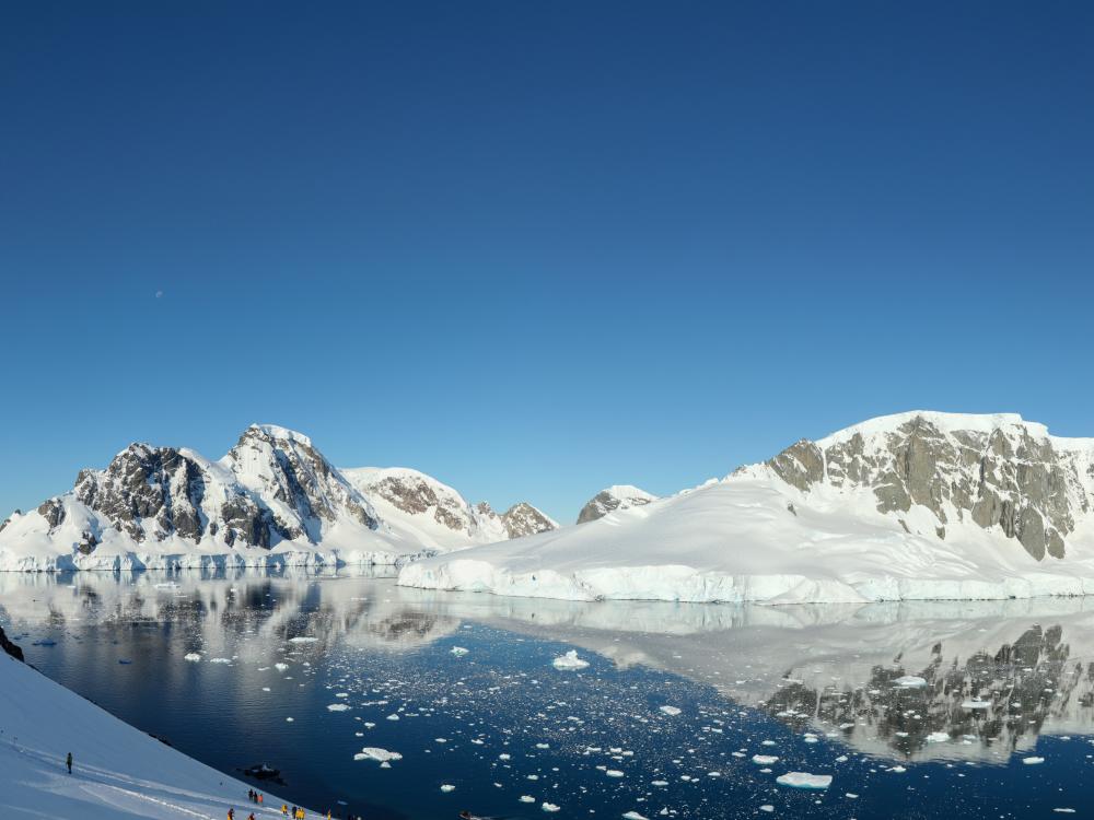 Snowy peaks reflected in still water on the Antarctic Peninsula