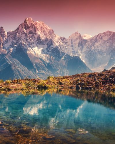 Wunderschöne Landschaft mit hohen Bergen und schneebedeckten Gipfeln, roter Himmel, der sich im See spiegelt Bergtal mit Spiegelung im Wasser bei Sonnenuntergang Nepal