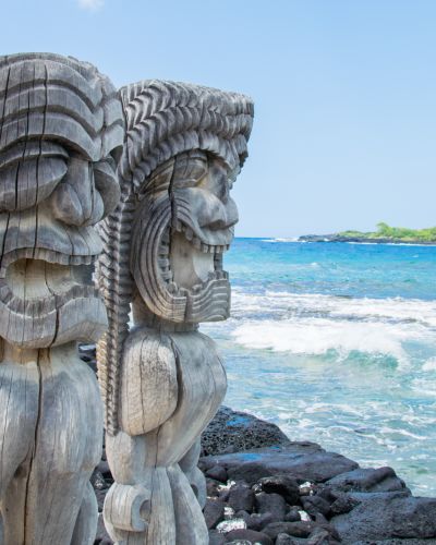 Ancient Polynesian Style Tiki Wooden Carvings Along The Beach Greet