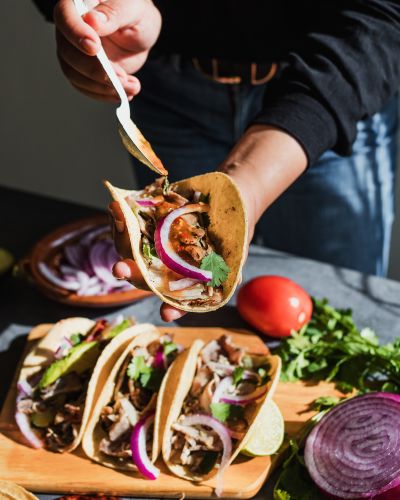 Mexican Woman Hands Preparing Tacos With Carnitas Pork And Sauce