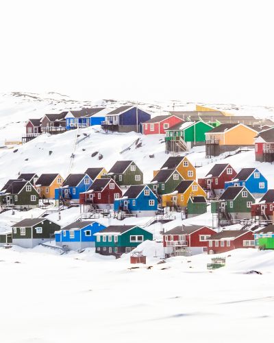 Multiple colorful Inuit houses and cottages on the hill covered in snow Aasiaat city Greenland Arctic