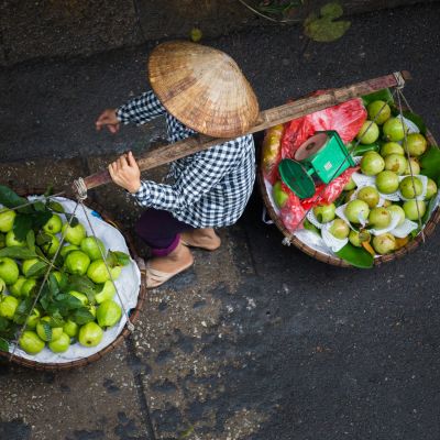 Man carries two baskets with fruits in the yoke, Vietnam, Asia