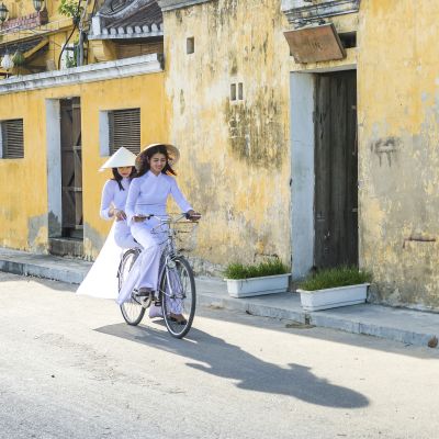 Vietnam girls with a vietnamese traditional costume wearing Ao dai ride a bicycle at Hua, Asia