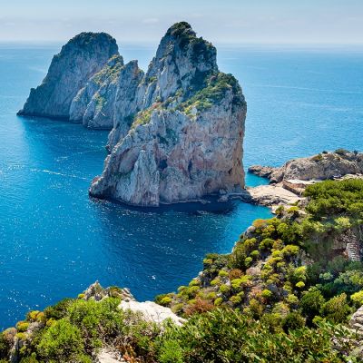 Enchanting Travels Italy Tours Faraglioni rocks view from hiking pass along Capri coastline , Italy.