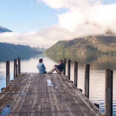couple in love sitting on the pier at Nelson Lake National Park in the South Island of New Zealand