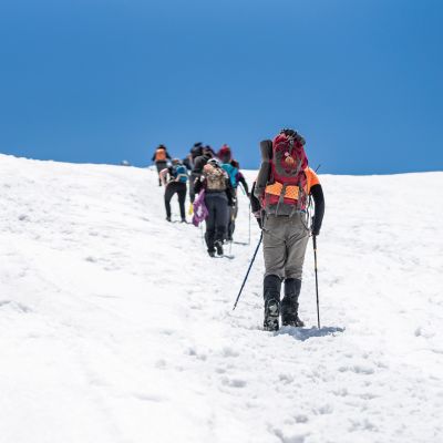 People doing trekking inside Andes valleys, crossing a snow valleys in central Chile at Cajon del Maipo, Santiago de Chile, South America