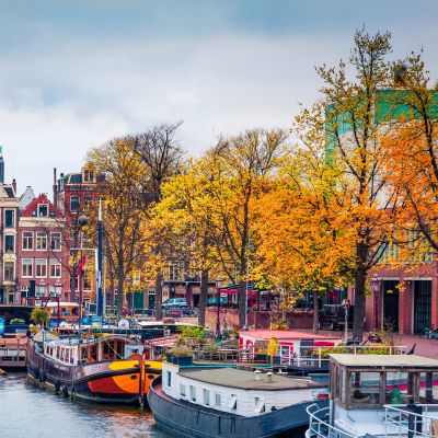 Panoramic autumn view of Amsterdam city. Famous Dutch channels and great cityscape. Gloomy morning scene of Netherlands, Europe. Traveling concept background. European Cities tours
