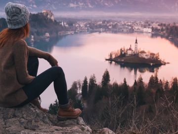 Woman looking on Bled Lake with Island, Castle and Alps Mountain on background.