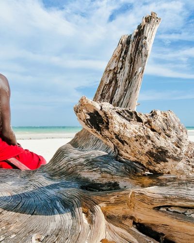 Enchanting Travels Tanzania Tours Man from the Maasai tribe sits on the shore of the Indian ocean - culture of Tanzania