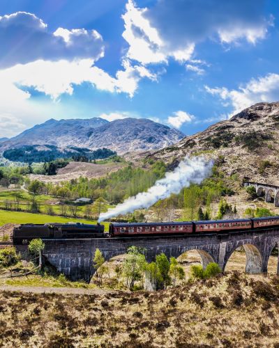 Glenfinnan Railway Viaduct in Scotland with the Jacobite steam train against sunset over lake