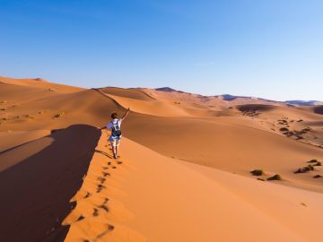 Tourist walking on the scenic dunes of Sossusvlei, Namib desert, Namib Naukluft National Park, Namibia.