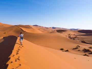 Tourist walking on the scenic dunes of Sossusvlei, Namib desert, Namib Naukluft National Park, Namibia.