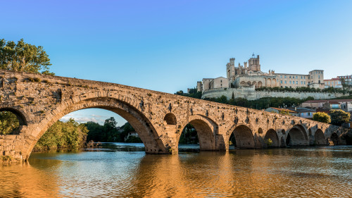 The historic stone bridge in Béziers spans the Orb River with Saint-Nazaire Cathedral in the background, offering a striking cultural landmark along the Canal du Midi.