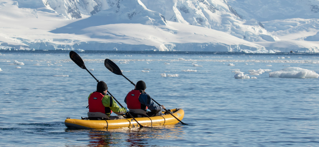 Two guests in dry suits paddle through Antarctic waters onboard our sit-on-top inflattable kayaks.