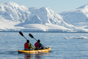 Two guests in dry suits paddle through Antarctic waters onboard our sit-on-top inflatable kayaks.