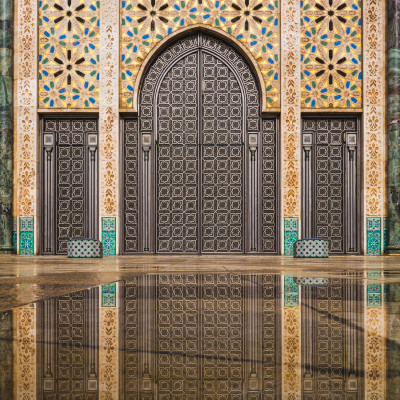 View of Hassan II mosque's big gate reflected on rain water, Casablanca, Morocco