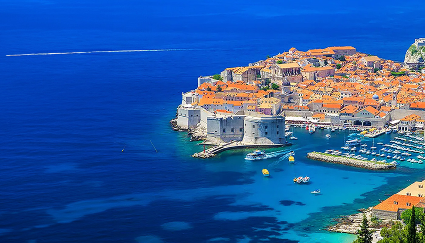 Stone walls surround the orange-roofed buildings in Old Town in Dubrovnik, Croatia, along the coast of the Adriatic Sea.