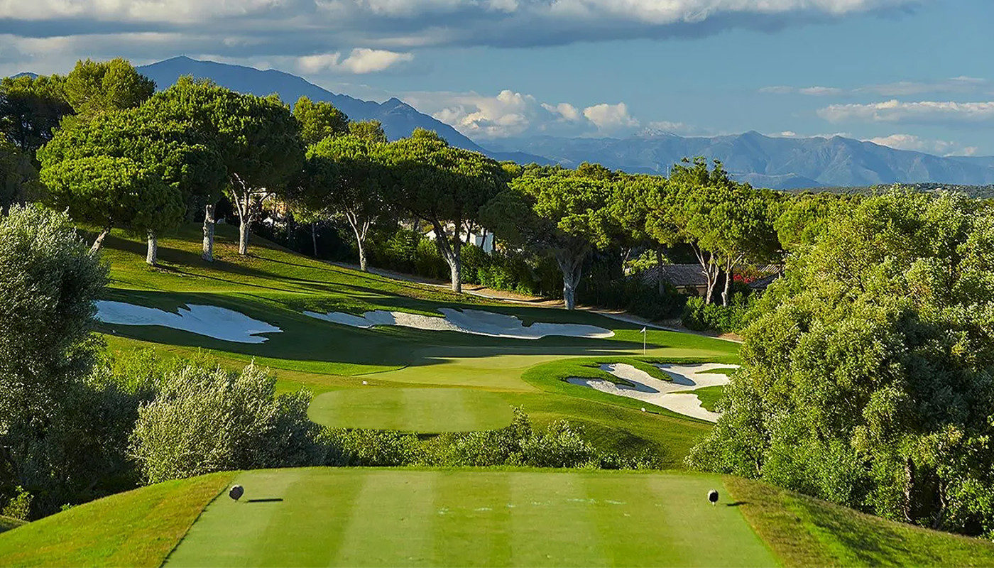 A tee box view of the 15th hole green at Real Club Valderrama framed by mountains in the distance in Sotogrande, Spain.