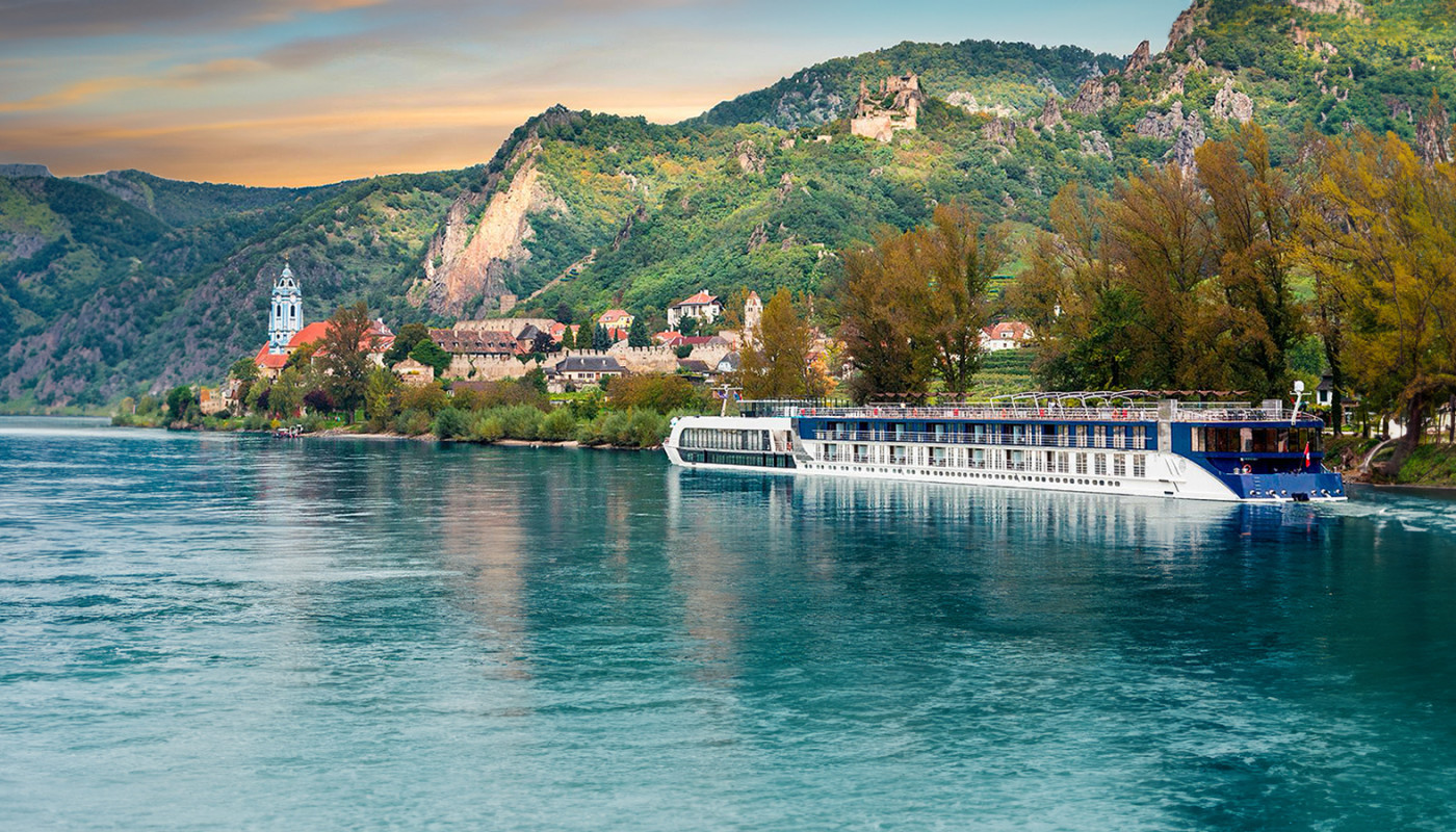 AmaSonata cruising on crystal clear turquoise water along a coastline.