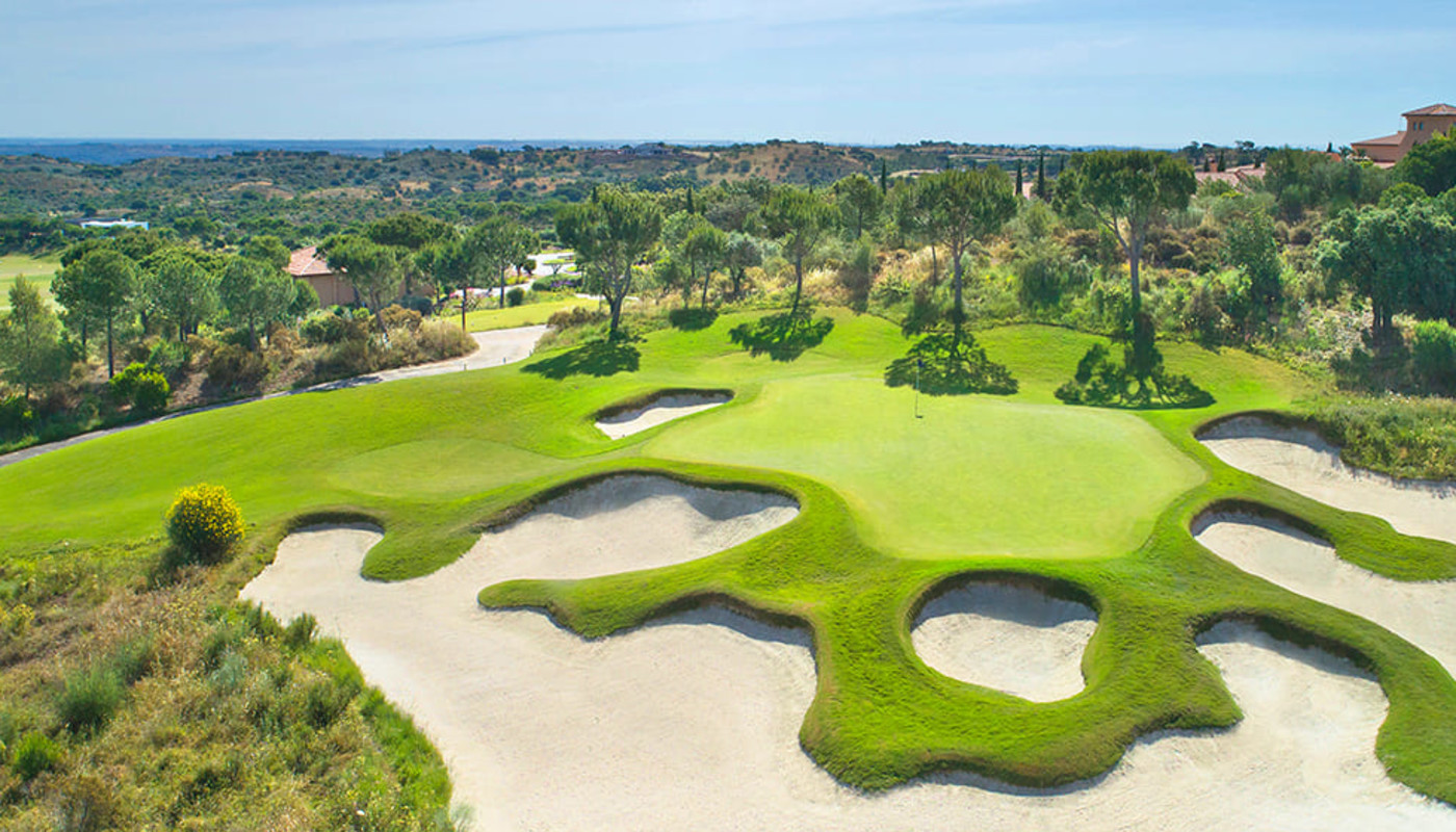 An aerial view of large winding bunkers surrounding the 9th green at Monte Rei Golf & Country Club on the southern coast of Portugal.