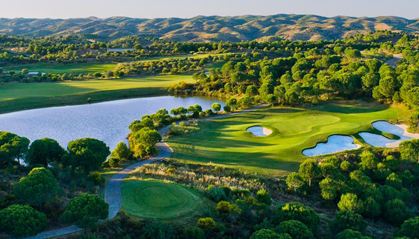 An aerial view of a hole surrounded by trees and bunkers at Monte Rei Golf & Country Club on the southern coast of Portugal.