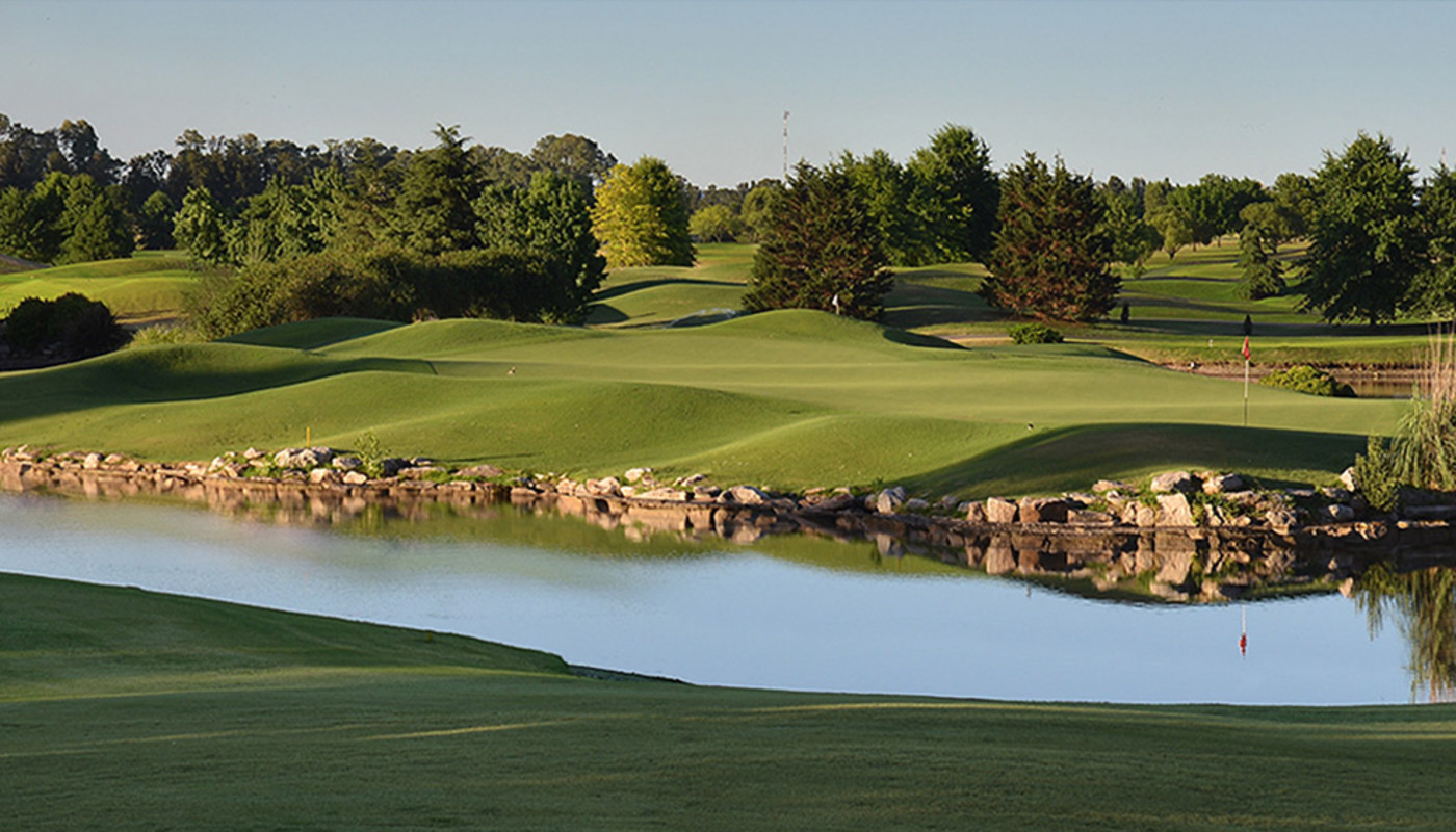 An island green surrounded by water, bunkers, and trees at Pilará Golf Club in Buenos Aires, Argentina.