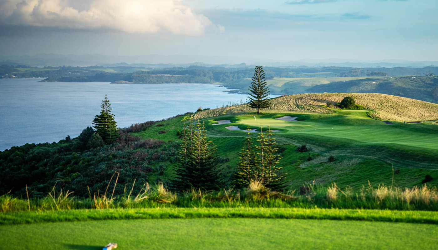 A tee box view of the 17th hole running up to a cliff overlooking the ocean at Kauri Cliffs Golf Course in Matauri Bay, New Zealand.