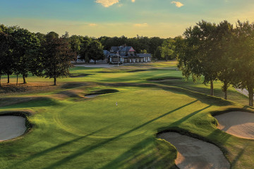 An overhead view of the 16th green surrounded by bunkers in front of the clubhouse at Chantilly Golf Club in Chantilly, France.