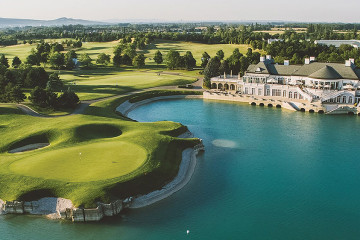 An aerial view of the 18th green at the edge of a lake in front of the clubhouse at Fontana Golf Club in Oberwaltersdorf, Austria.