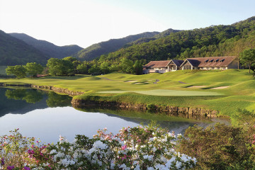 A green at Golden Valley Golf Club meets the edge of a lake under a distant view of mountains just outside of Osaka, Japan.