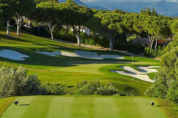 A tee box view of the 15th hole green at Real Club Valderrama framed by mountains in the distance in Sotogrande, Spain.