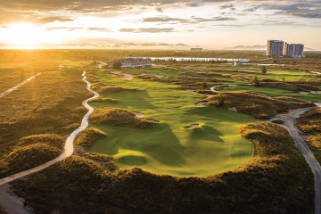 An aerial view of a long rolling fairway leading to a green at Hoiana Shores Golf Club in Quảng Nam, Vietnam.