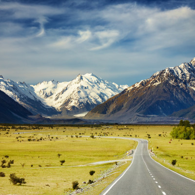road towards mountains with snow caps in Southern Alps New Zealand