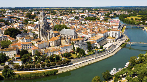 Luchtfoto van Saintes met de romaanse kathedraal en rood betegelde daken aan beide zijden van de rivier de Charente.