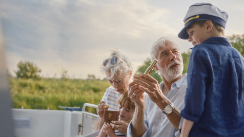 Grandparents teaching grandchildren on a boating adventure with curiosity and joy.