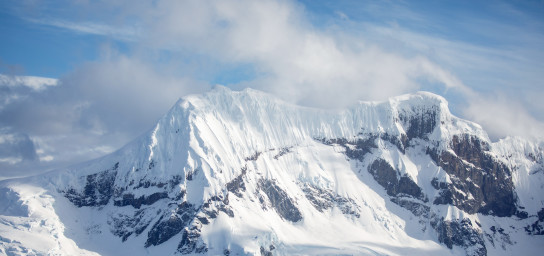 A snow covered mountain emerging from the Antarctic ocean