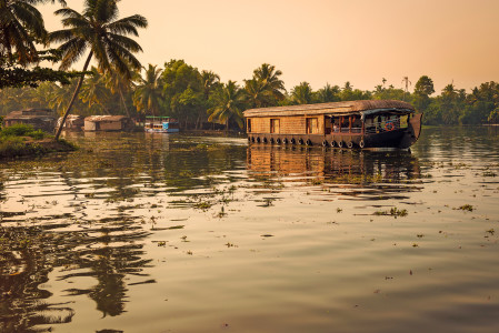 Goldene Abendstimmung mit Blick auf ein Hausboot in den Backwaters von Kerala