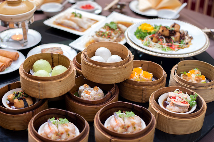 Anordnung verschiedener Dim Sum in diversen Bambuskörben auf einem Tisch in einem chinesischen Restaurant