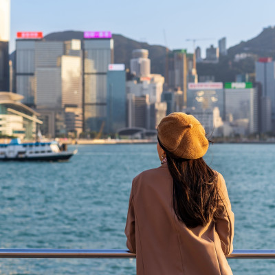 Junge Frau guckt auf die Skyline im Victoria Harbour Hongkong
