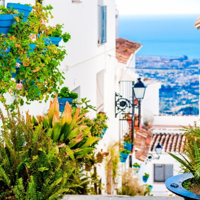 ls Spain Tours Picturesque street of Mijas with flower pots in facades. Andalusian white village. Costa del Sol. Southern Spain