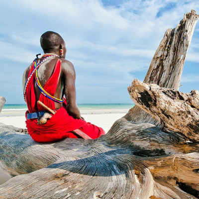 Enchanting Travels Tanzania Tours Man from the Maasai tribe sits on the shore of the Indian ocean - culture of Tanzania