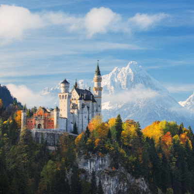 Germany. The famous Neuschwanstein Castle in the background of snowy mountains and trees with yellow and green leaves