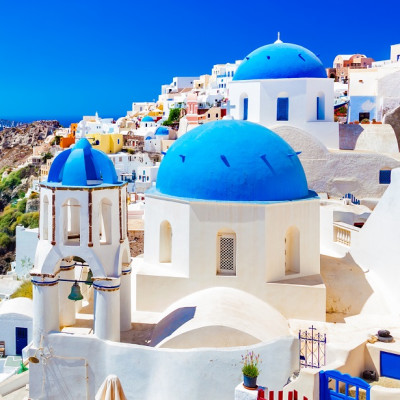 Oia town on Santorini island, Greece. Traditional and famous houses and churches with blue domes over the Caldera, Aegean sea - Greece Vacation