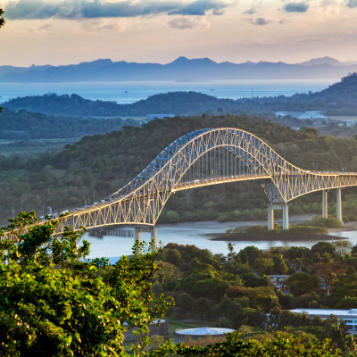Panoramic aerial view of the Bridge of The Americas over the Panama Canal Pacific Entrance. Sunset scene with a gentle mist in the background. The bridge is spanning two continents - two Americas.