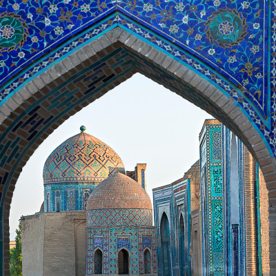 Blick durch ein Toröffnung auf die Mausoleen und Kuppeln des historischen Friedhofs von Shahi Zinda, Samarkand, Usbekistan