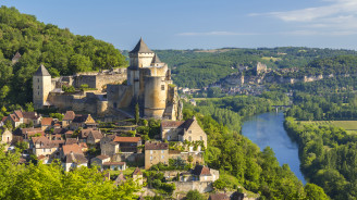 Un castillo medieval se alza sobre un río y una ciudad en una colina en Aquitania.