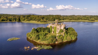 Drone view of the ivy-covered ruins of a castle on a small island in Lough Key.