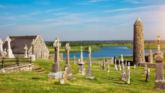 Ancient round tower and Celtic high crosses at Clonmacnoise overlooking the River Shannon.