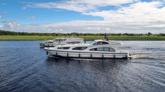 Cruise boats travel across Lough Key towards the horizon under a cloudy sky.