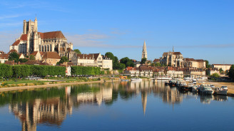 Uitzicht op een historische stad in Bourgogne aan de rivier met stenen bruggen, gotische kathedralen en aangemeerde boten.